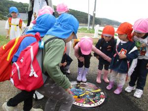 子ども達がマンホールを見ている写真